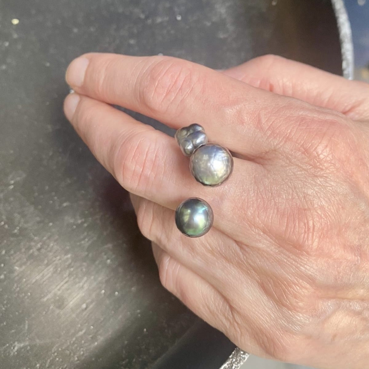 Bague ouverte présentant deux perles de Tahiti sculptée,de couleurs différentes et une perle keshi carrée.L'anneau en argent est orné de petites pierres de couleurs.