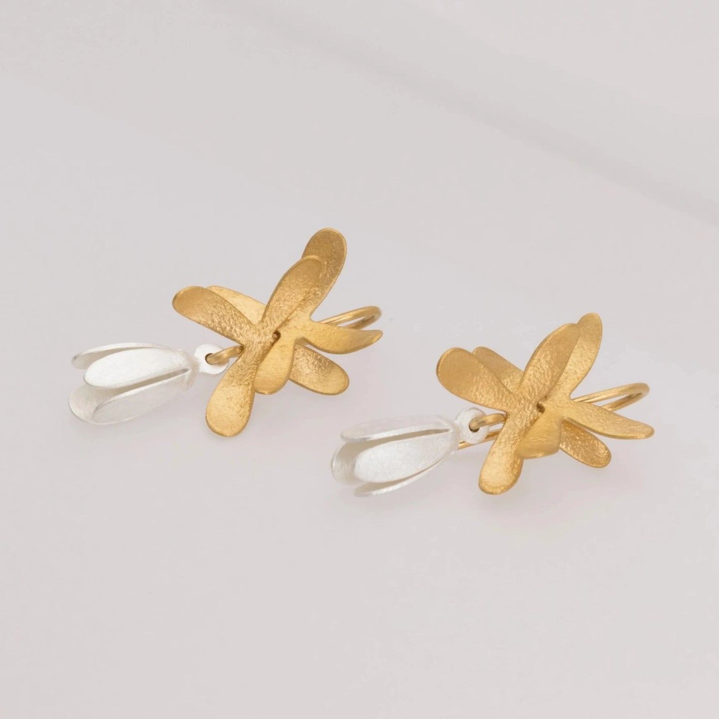 Boucles pendantes représentant un perce-neige. Une fleur en forme de clochette en argent est suspendue sur un fermoir crochet. Son feuillage est en argent plaqué or jaune.