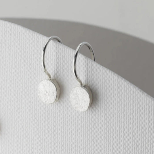 Petites boucles d'oreilles pendantes composées de deux éléments ronds superposés en forme de galet en argent brossé. Fermoirs crochets.