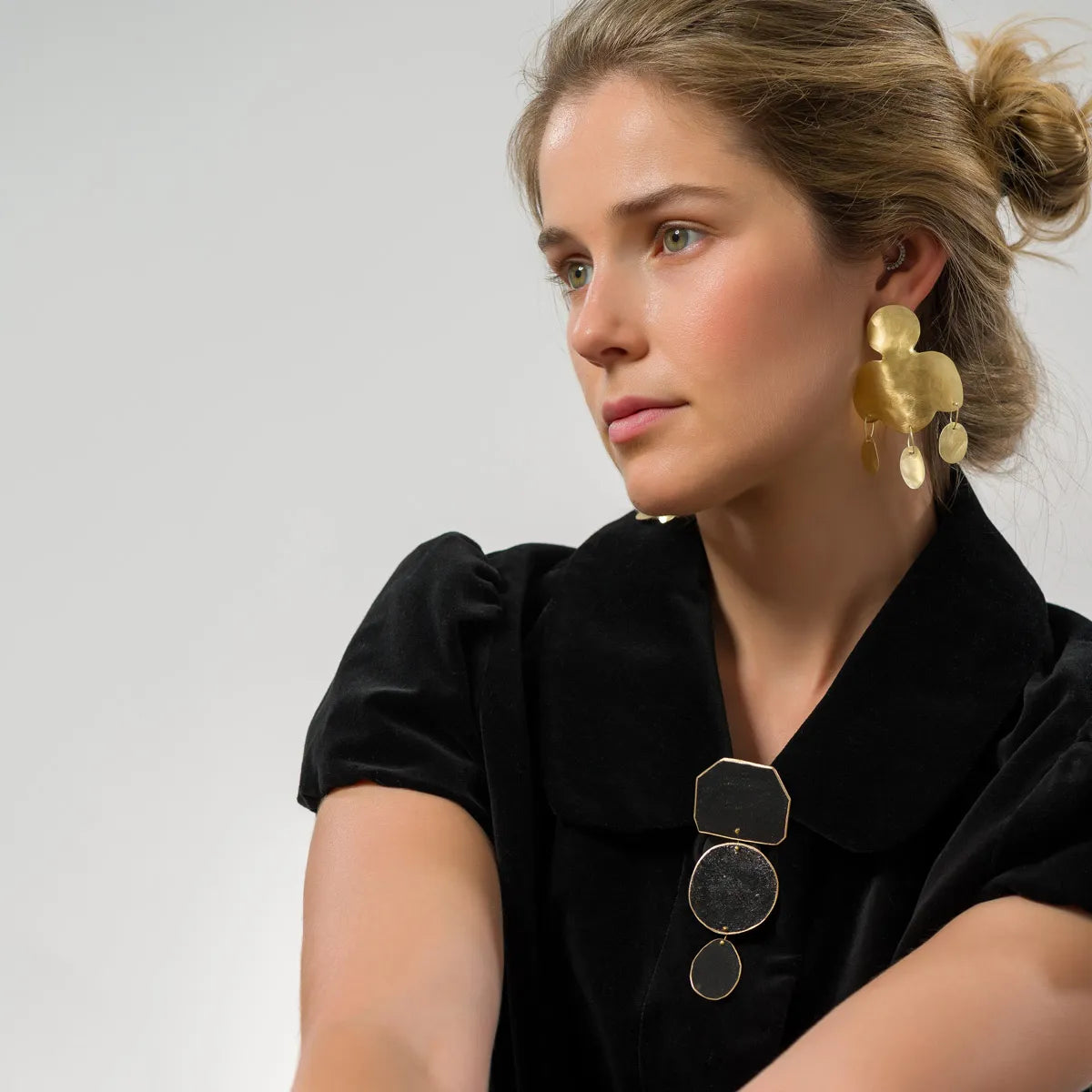 Cette paire en bronze doré, se distingue par une découpe aux lignes arrondies et de trois pampilles allongées, alliant minimalisme et inspiration historique.