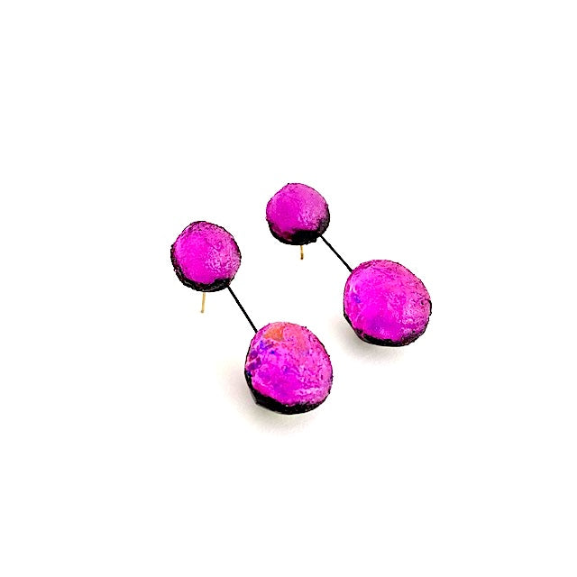 Boucles pendantes en résine rose fuchsia composées de deux sphère en résine texturée et irisée, reliées par un câble noir. Pour oreilles percées. Photo de profil.