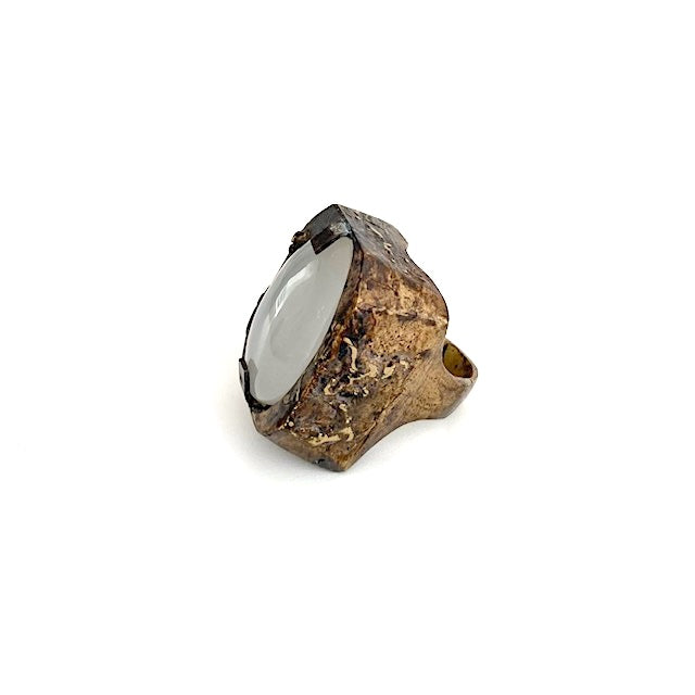 Bague Sculpturale rectangulaire en bronze patiné et texturé accueille une grande agate blanche ovale tenue par deux griffes de chaque côté. Bijou de profil.