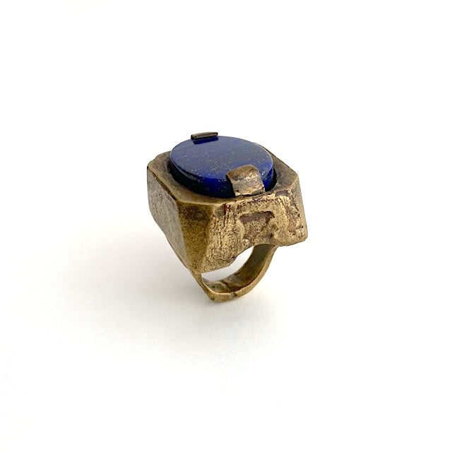 Bague sculpturale rectangulaire en bronze au centre un lapis-lazuli taillé ovale est serti par deux griffes de chaque côté.