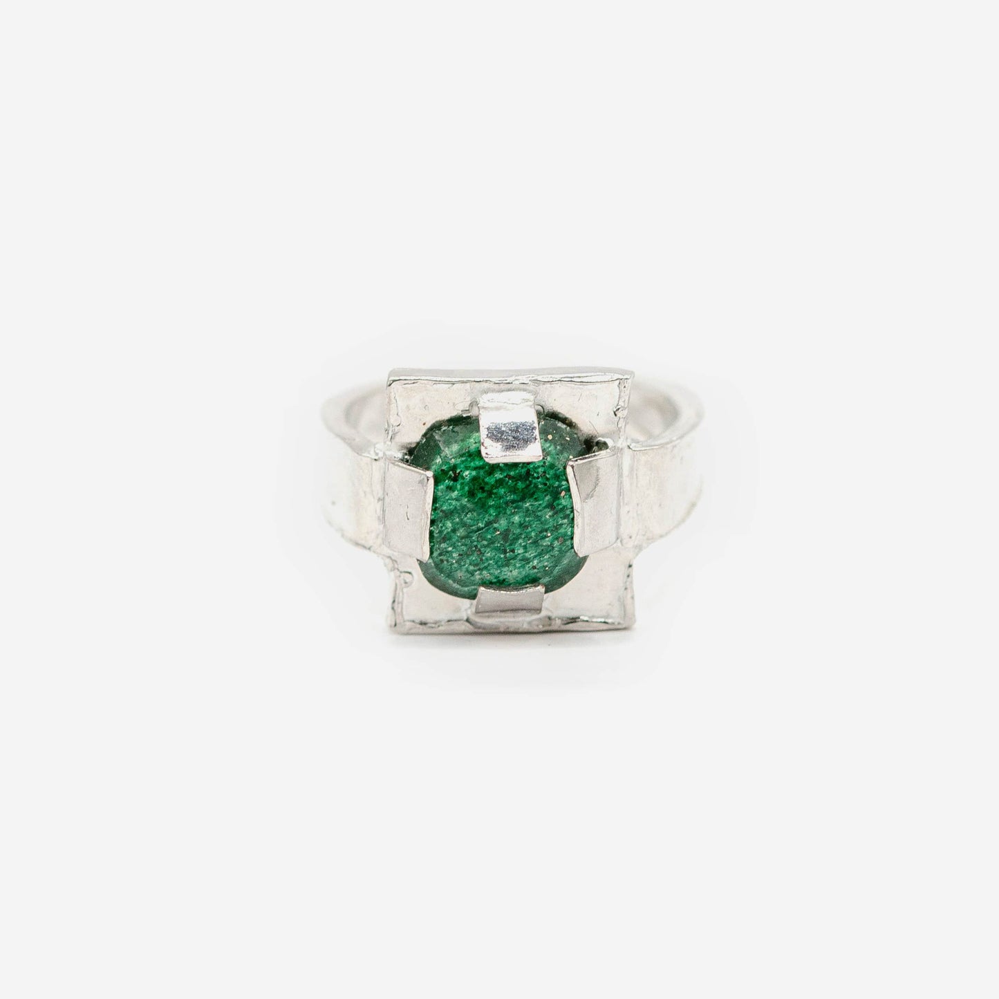 Bague carrée en argent et jade vert facetté. Plutôt que de simplement maintenir le jade, le sertissage devient ici une véritable structure sculpturale, dessinant un cadre irrégulier qui souligne la présence de la pierre.
