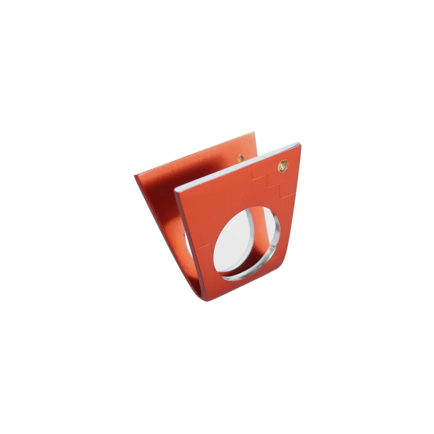 Bague graphique en aluminium anodisé orange. Sur ses deux faces aux lignes gravées se détache une tourmaline jaune. Bague de profil sur fond blanc.