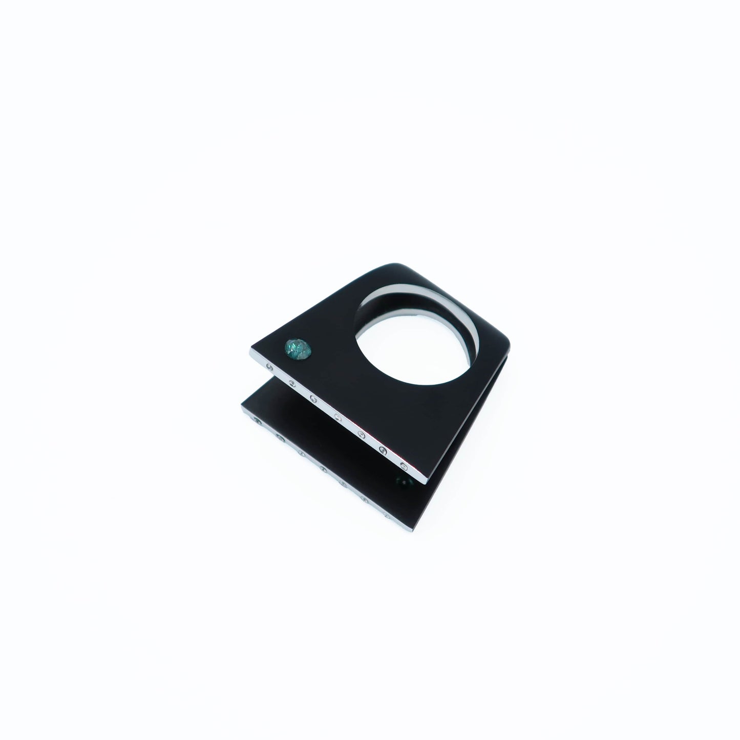 Bague Design en aluminium noir ornée d'un diamants bleu-vert sur chacune des deux faces. Bague posée sur fond blanc.