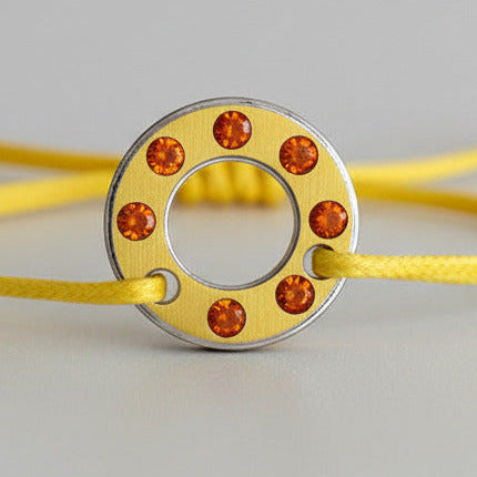 Bracelet Ready-Made, rondelle en aluminium jaune serti de six opales de feu. bijou contemporain et unisex présenté sur lien de coton réglable jaune.