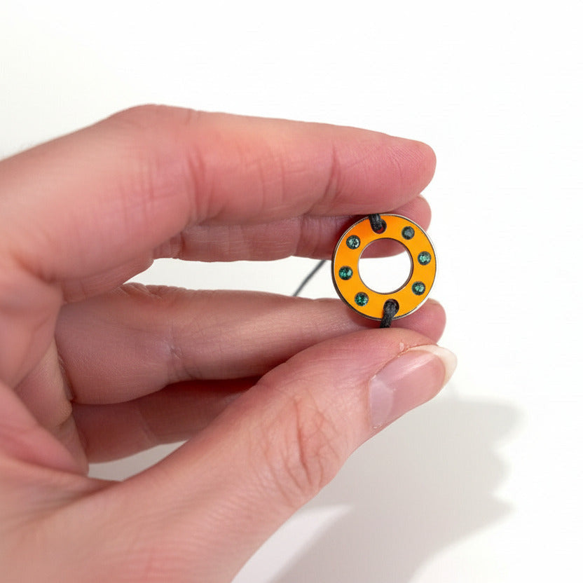 Bracelet Ready-Made, petit modèle est façonné d'une rondelle en aluminium orange et six tourmalines vertes. bijou upcyclé, présenté sur lien de coton réglable. Un bracelet unisexe au design contemporain à porter au quotidien.