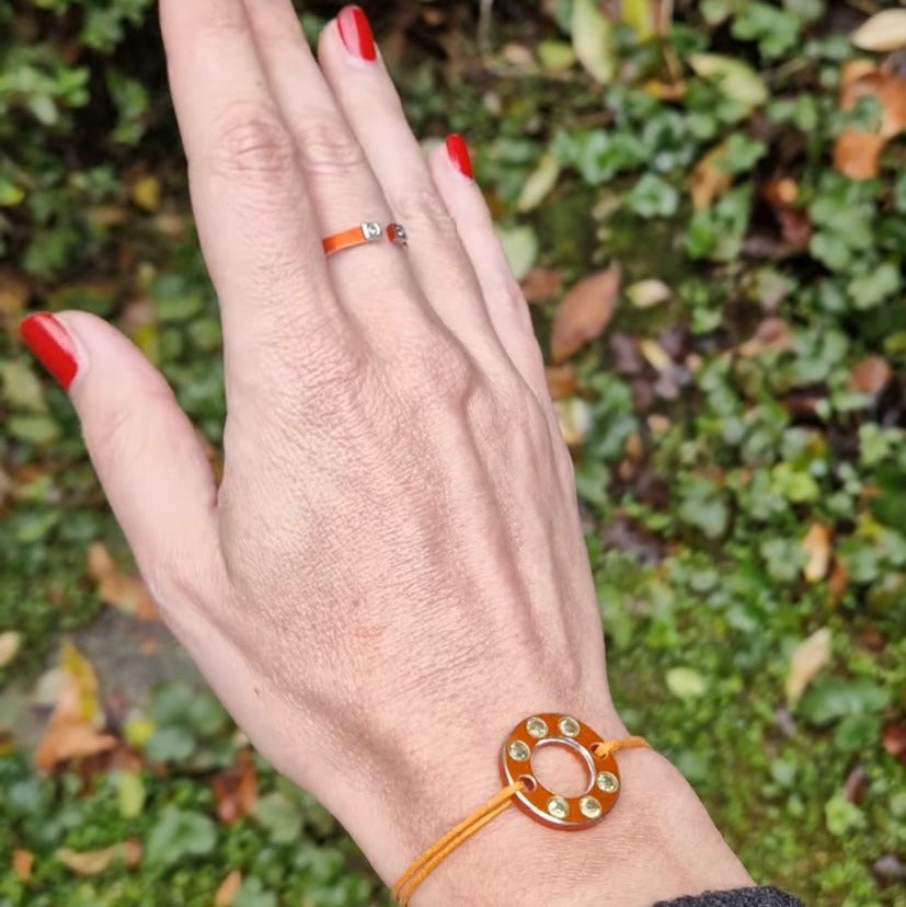 Bracelet Ready-Made en rondelle d'aluminium orange, sertie de six péridots. Un bracelet design, présenté sur lien de coton ciré orange. vue portée