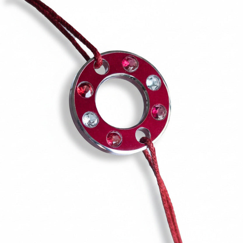Bracelet Ready-Made, rondelle d'aluminium rouge sertie de quatre spinelles rouge et deux aigue-marines. Un bracelet contemporain et unisexe présenté sur lien de coton ciré rouge.