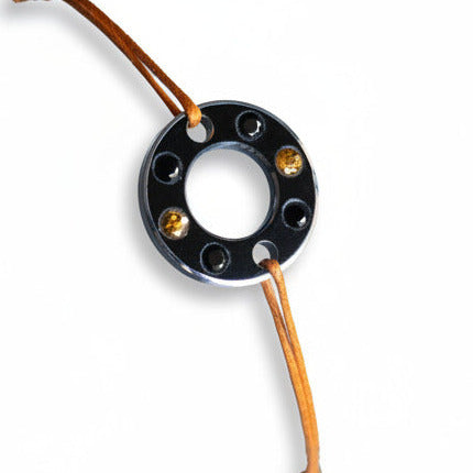 Bracelet Ready-Made, rondelle d'aluminium noir sertie de quatre spinelles noirs et deux saphirs oranges. Un bracelet contemporain et unisexe présenté sur lien de coton ciré orange.