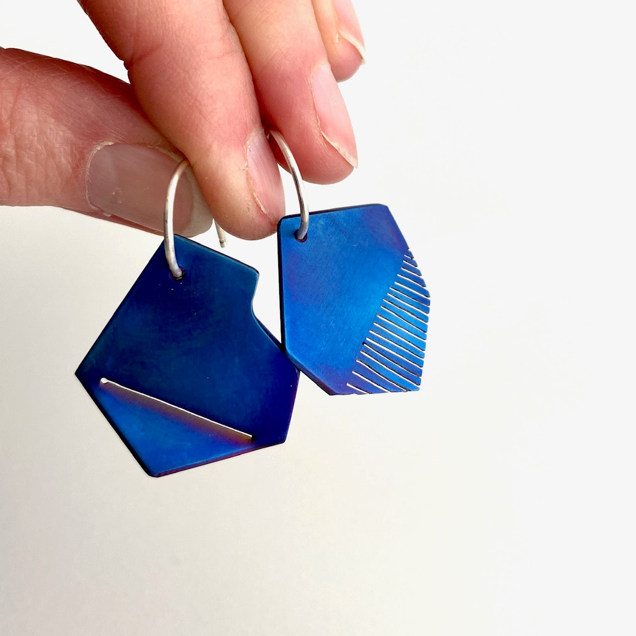 Boucles d'oreilles asymétriques en titane bleu plié et scié montées sur tiges d'argent formes créoles
