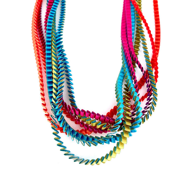 Long sautoir coloré composé de huit bandes de satin plissé turquoise, doré rouge,orange, violet,fuchsia reliées les unes aux autres par un lien de coton jaune.