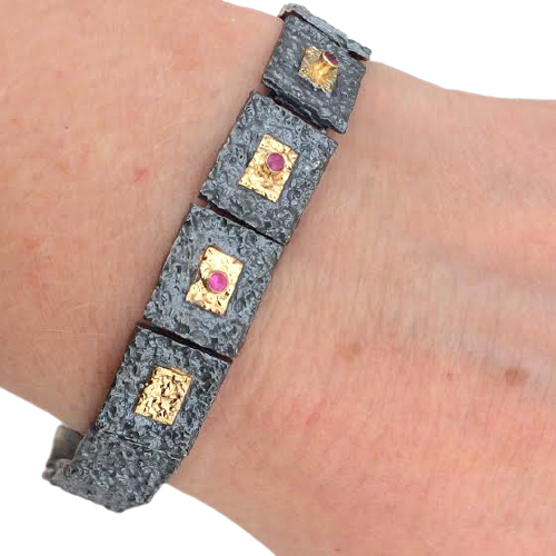 Bracelet articulé argent patiné, composé de 13 éléments rectangulaires, ornés de 5 rectangles or jaune et 3 rubis sertis.