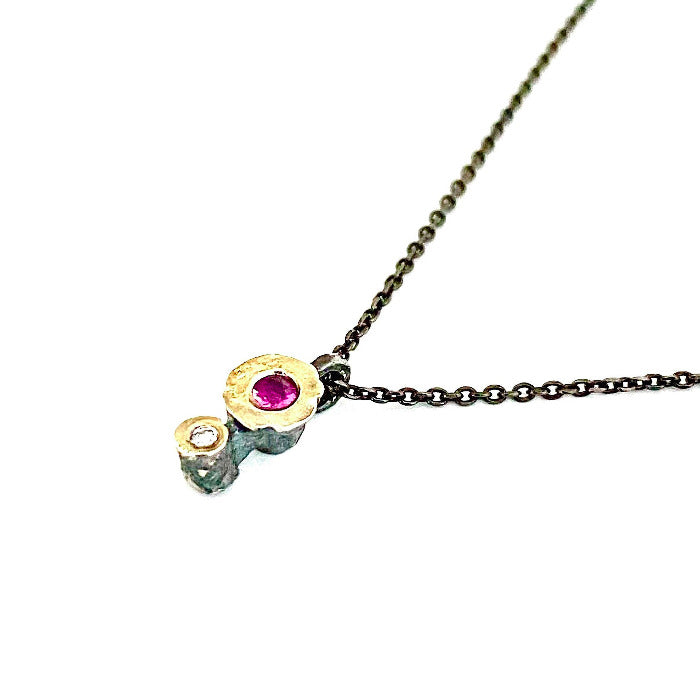 Pendentif minimaliste argent patiné et or jaune serti d'un rubis et d'un diamant taille brillant, chaîne fine argent patiné.