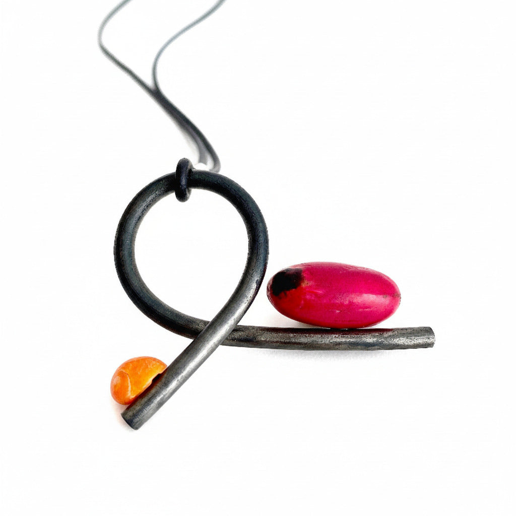 Pendentif en fer forgé paré d'un coquillage escargot orange et d'une graine rose framboise du Mali. presenté sur lien de caoutchouc, pièce unique 2017