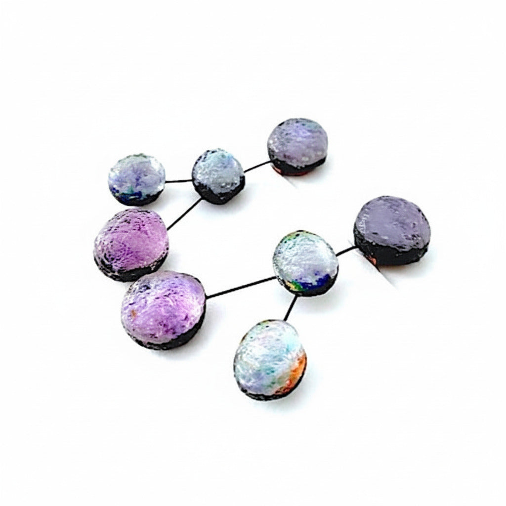 Boucles d'oreilles en résine irisée dans des tons de mauve.clips constituée de 4 sphères reliées les unes aux autres par cable noir.