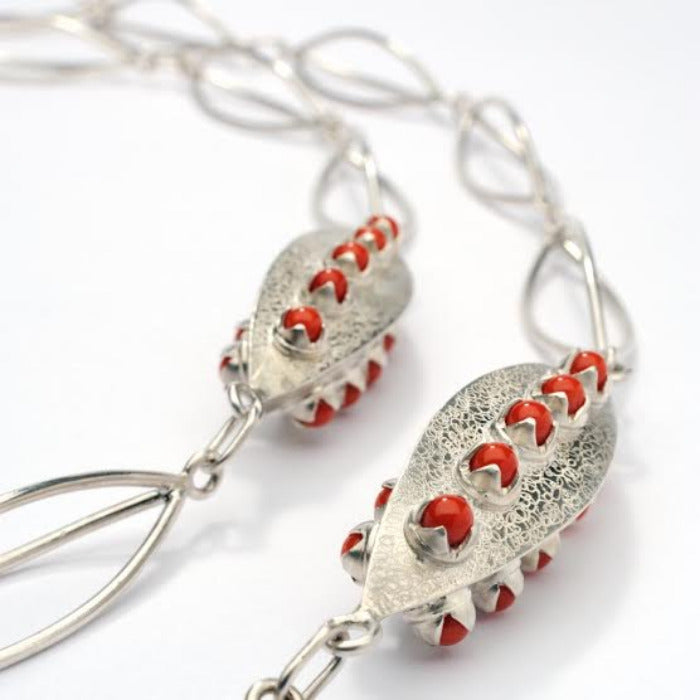 Sautoir argent composé de 15 anneaux de forme ogive et de 2 éléments finement guillochés sertis chacun de 15 perles de corail de Méditerranée.