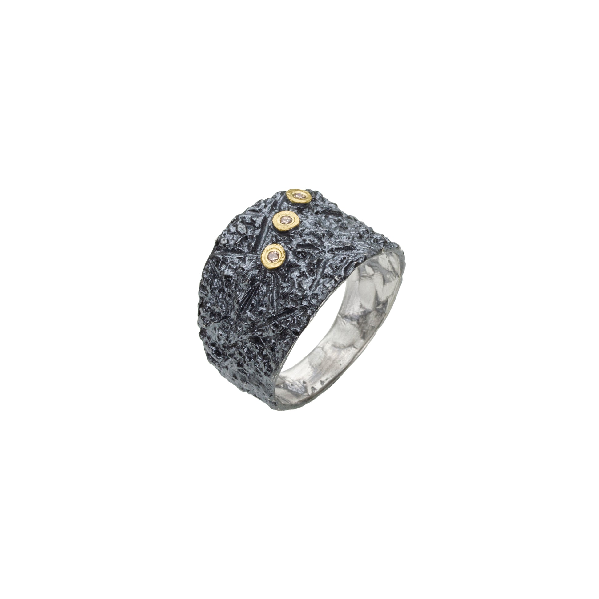 Cette bague en argent patiné et texturé se distingue par trois diamants taille brillant, sertis en or jaune sur dessus, alignés de côté.
