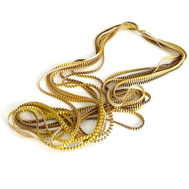 Long sautoir de couleur ivoire , kaki et doré composé de huit bandes de trois millimètres de satin plissé reliées les unes aux autres par un lien de coton jaune d'or.