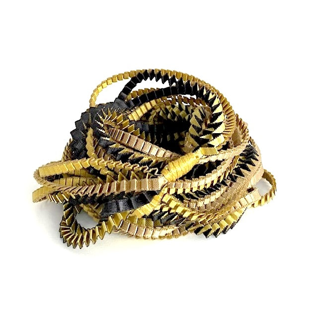 Long sautoir de couleur olive, noir et doré,composé de huit bandes de trois millimètres de satin plissé reliées les unes aux autres par un lien de coton jaune d'or. 