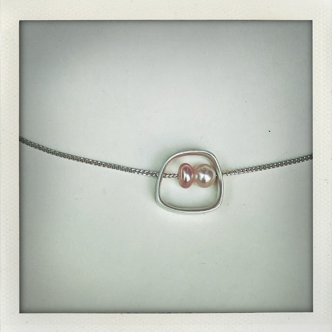 Pendentif géométrique en argent texturé avec perles d’eau douce blanche et rose. Détail du pendentif minimaliste Perlimilb avec chaîne réglable en argent traversante. Création artisanale d'Anne Milbeau.