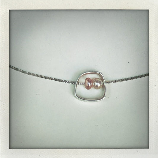 Pendentif géométrique en argent texturé avec perles d’eau douce blanche et rose. Détail du pendentif minimaliste Perlimilb avec chaîne réglable en argent traversante. Création artisanale d'Anne Milbeau.
