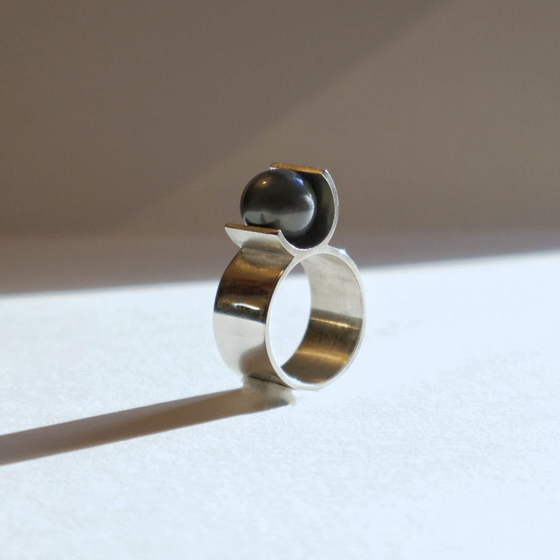 Bague contemporaine en argent en forme de U avec perle noire de Tahiti ronde 9 mm. Une création signée Atelier Grandval.