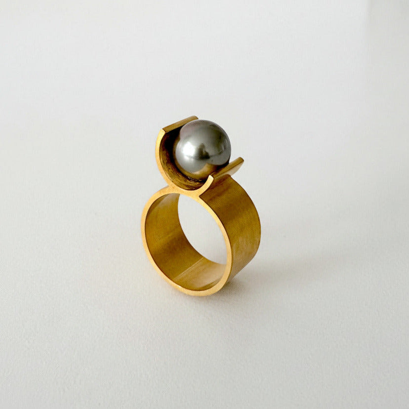La bague 8 en vermeil se distingue par une architecture minimale : un corps en forme de U vient délicatement soutenir une perle de  Tahiti grise de 9 mm, comme en suspension.