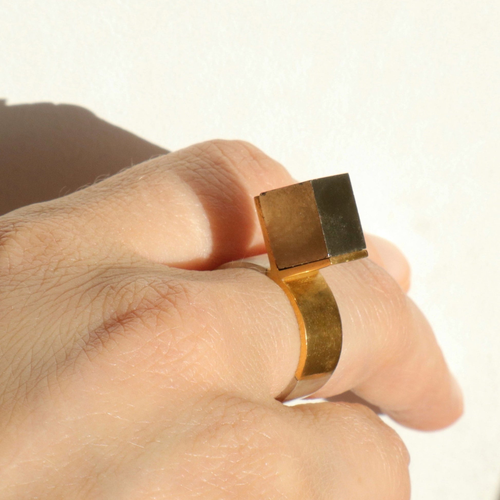 Bague X en argent et vermeil avec cube de pyrite naturelle, détail du serti, bijou porté.
