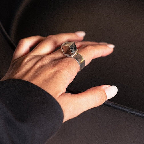 Bague design circulaire mettant en valeur une pyrite. Détail de la pierre brute sertie dans une bague en argent. Bijou porté.