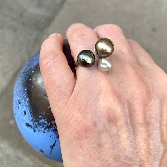 Bague ouverte présentant trois perles de Tahiti de couleurs différentes. L'anneau en argent sculpté est orné de petites pierres de couleurs.