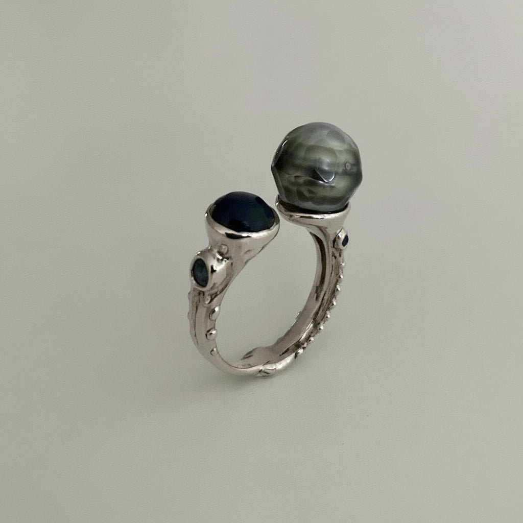 Bague contemporaine "Toi et Moi" en argent ciselé, avec d'un côté, une perle de Tahiti sculptée et de l'autre une opale bleue en cabochon et aigue-marine. Ue pièce unique faite à la main par Ivan Michelson.