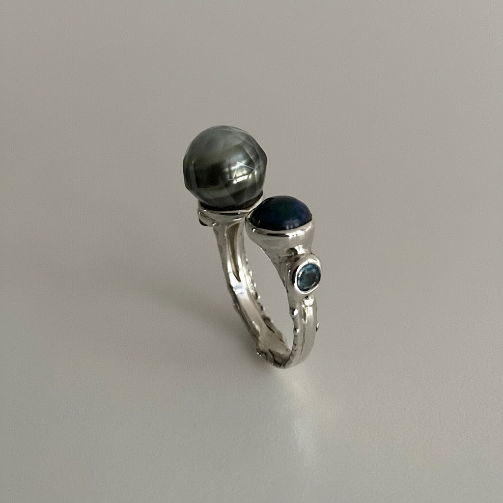 Bague contemporaine forme Toi et Moi" en argent ciselé, avec d'un côté, une perle de Tahiti sculptée et de l'autre une opale bleue en cabochon accompagnée d'une aigue-marine. Une pièce unique faite à la main par Ivan Michelson.