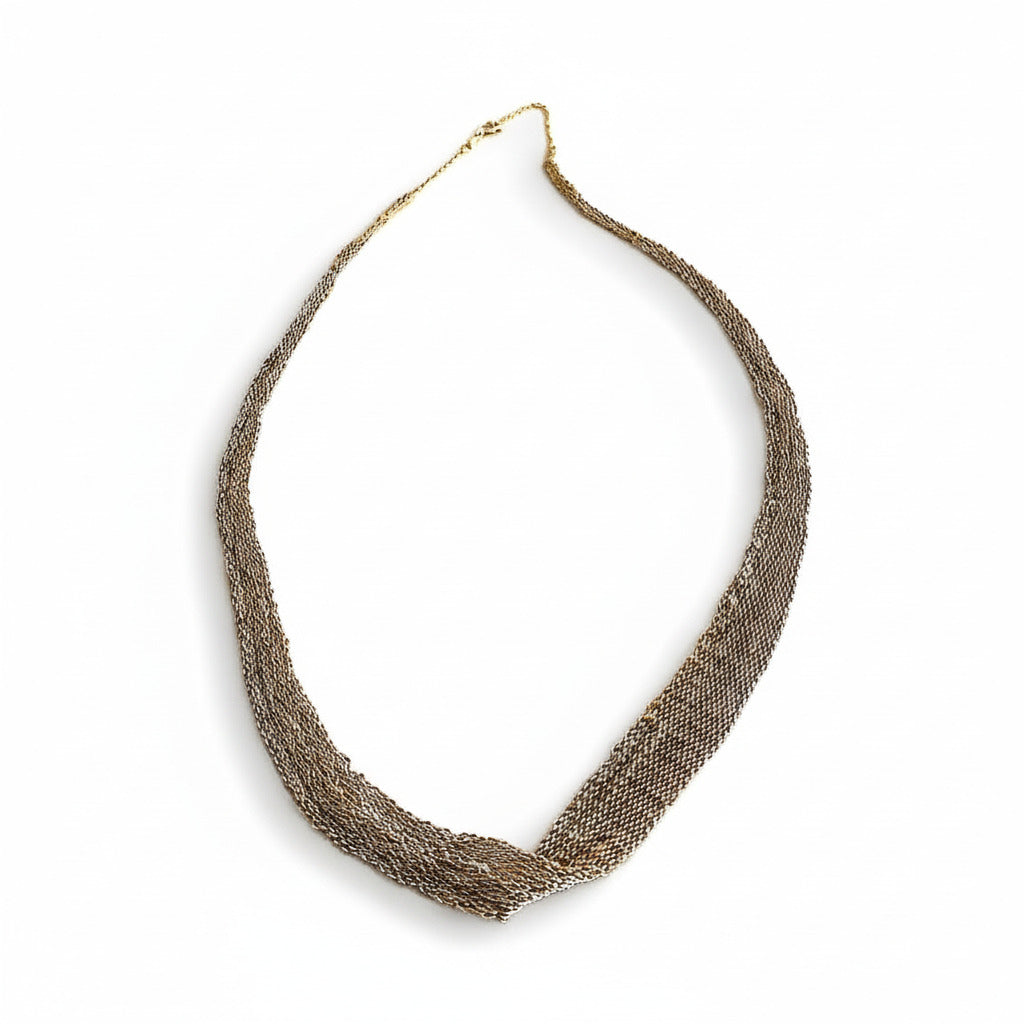 Tour de cou en forme de ruban dégradé, réalisé par un assemblage de chaînes d'argent et dorées au fil de soie. Un collier minimaliste fait main par l'artiste belge Ria Lins.