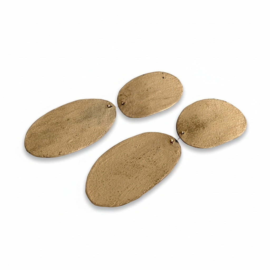 Boucles XL beige en bronze laminé ultra-léger. Peintes à la main, elles offrent une silhouette géométrique moderne composée de deux ovales reliés.