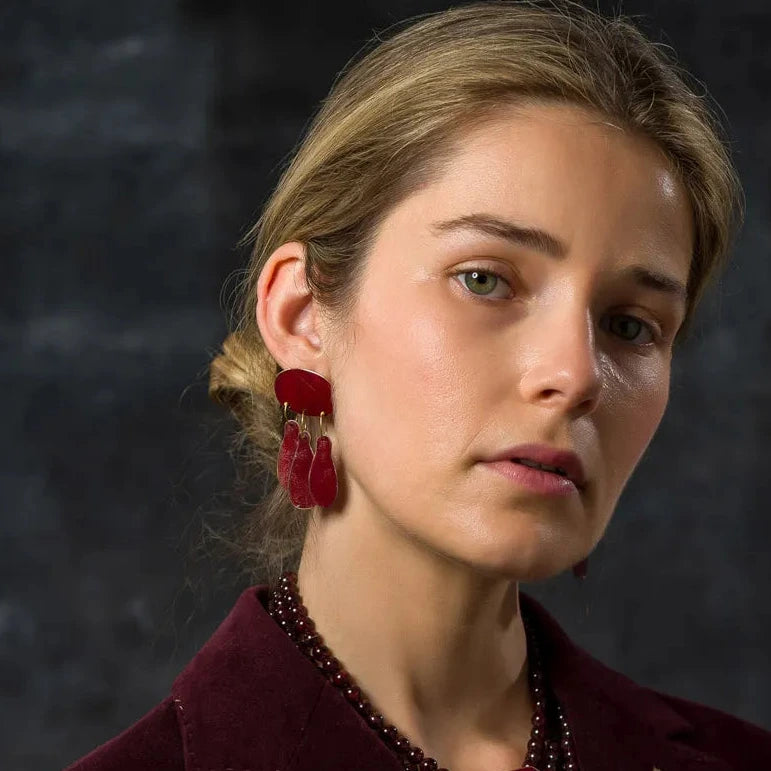 Boucles d’oreilles Héritage en bronze laminé peint à la main avec des pigments acrylique bordeaux. Un ovale et trois pampilles. Bijoux portés.