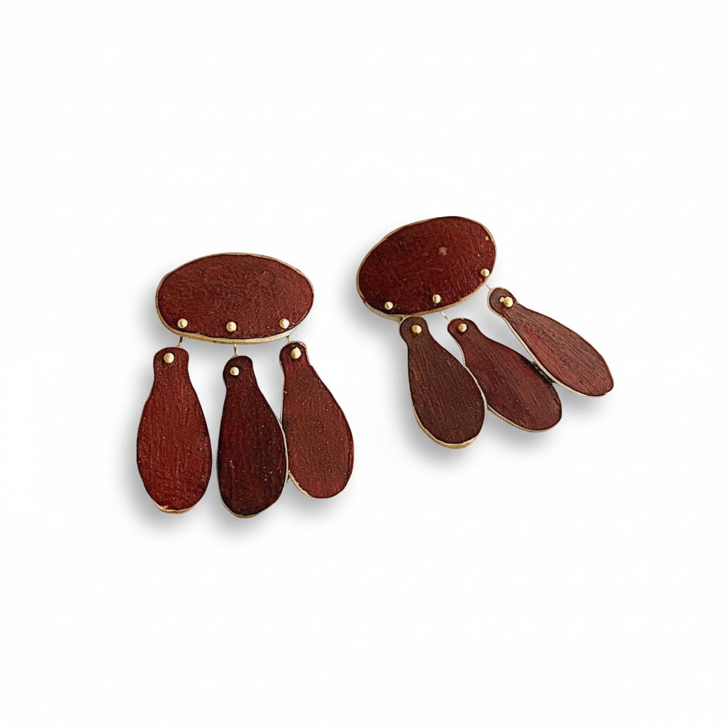 Paire de boucles d'oreilles réinterprétée de bijoux du XIIIe siècle, en bronze laminé, composée d’un ovale et de trois pampilles allongées, allie lignes historiques et design minimaliste. Elles sont peintes à la main avec des pigments acryliques bordeaux.