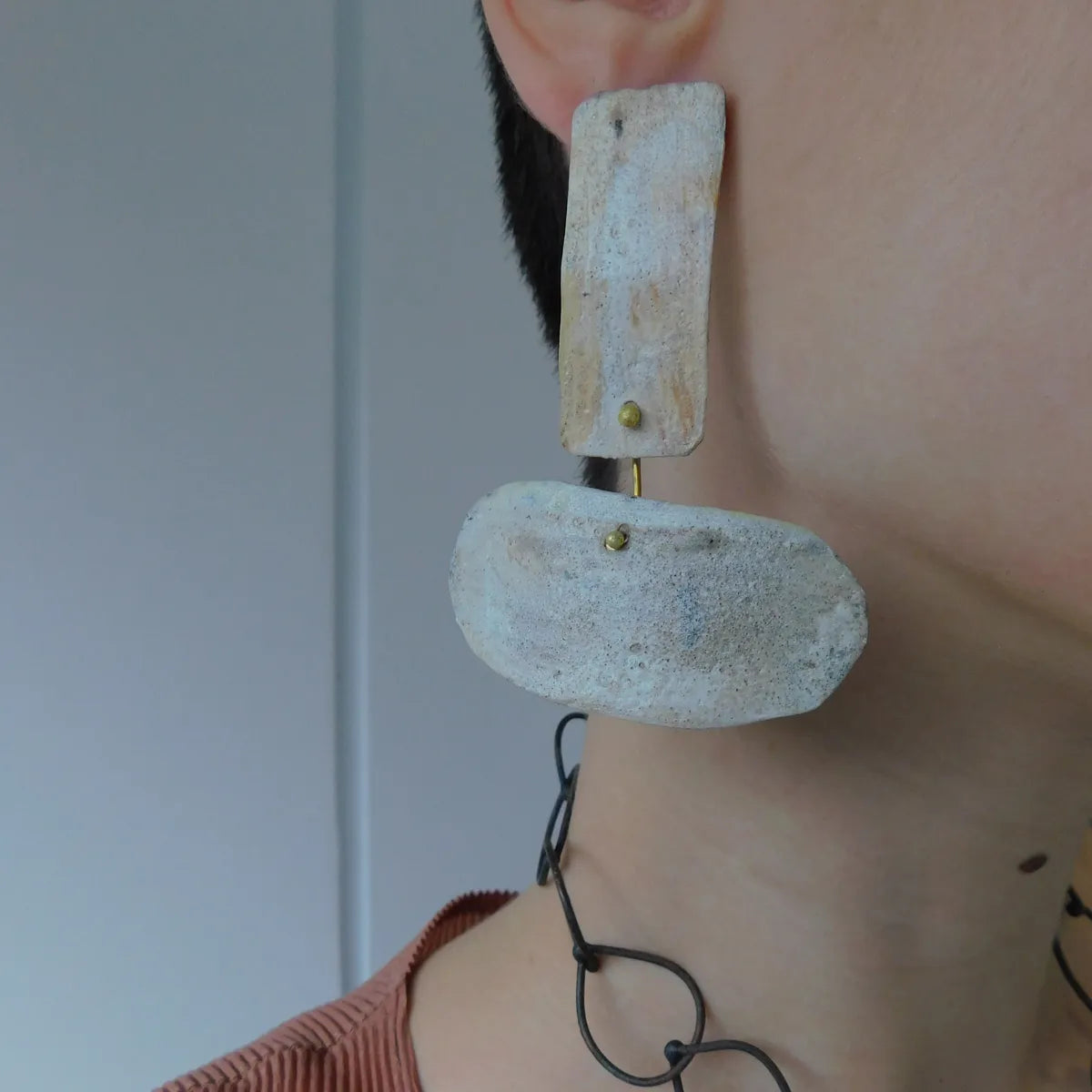 Boucle XL associe deux formes géométriques reliées, façonnées en bronze laminé et peintes à la main. Bijou porté vue de profil.