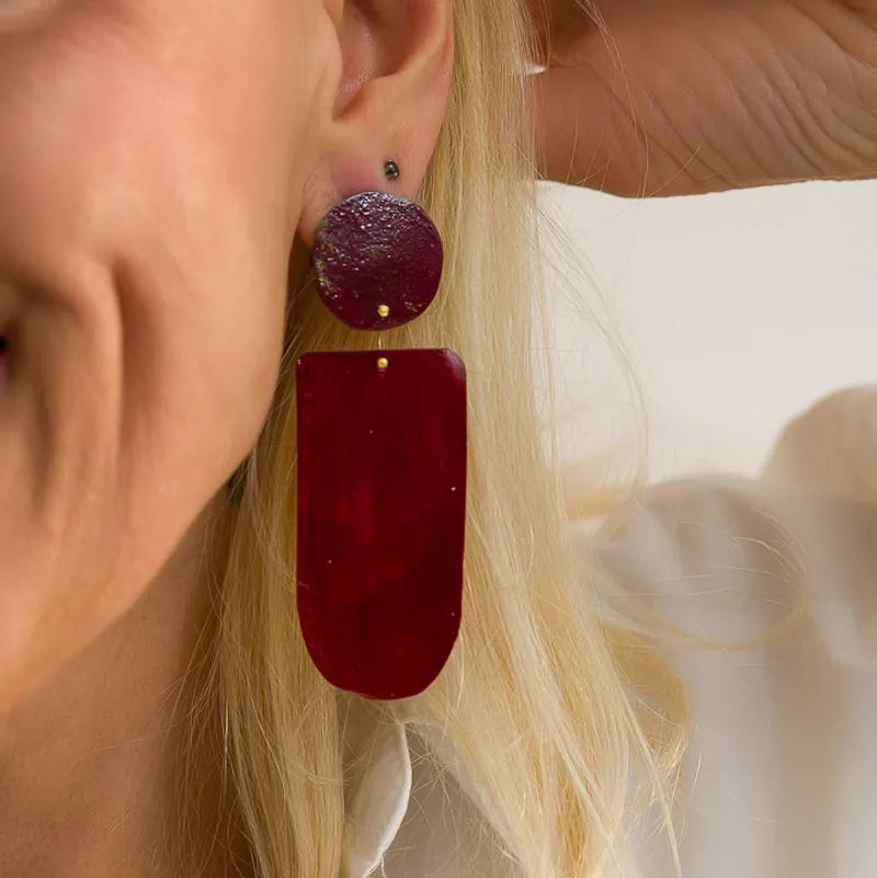 Boucles d’oreilles XL en bronze peint à la main par Dora Haralambaki. Légères, géométriques et uniques, alliant couleur, art et artisanat. Détail, boucle portée.