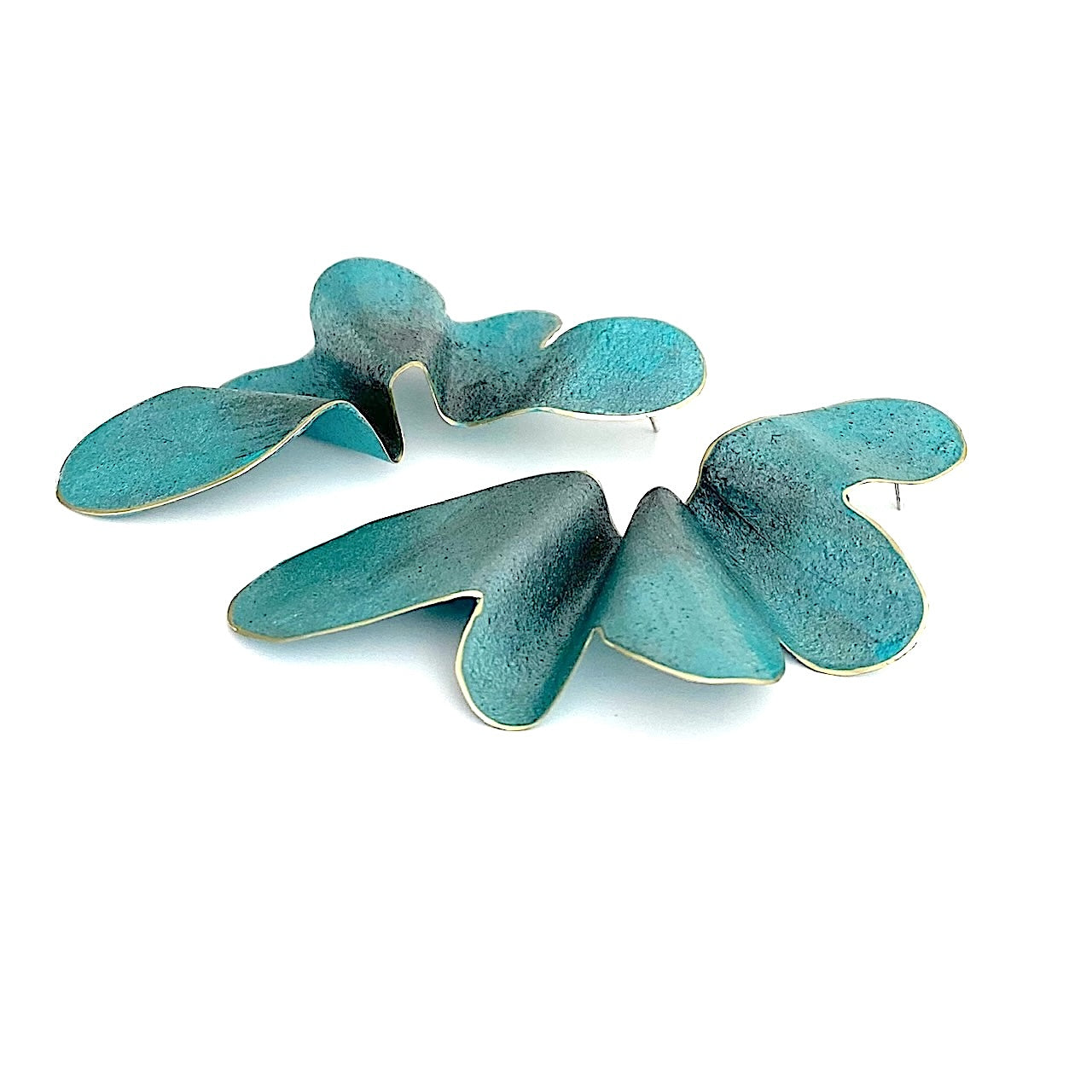 Boucles d'oreilles bleu clair en bronze laminé et peintes à la main, elles présentent une forme de demi-fleur minimaliste, légère et aérienne. Vue de profil. Une création 
Leur volume XL reste confortable grâce au métal laminé. Une création contemporaine signée Dora Haralambaki.
