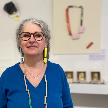 Longues boucles d’oreilles graphiques en bois et formica. Portées de façon dépareillée, l'une est jaune et l'autre bleu clair.