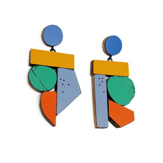 Suspendues à un support rond bleu, ces boucles XL mêlent bois et formica mat ou brillant, rayé ou ponctué de petits points noirs. Leur design épuré met en valeur des éléments assemblés entre eux de couleurs franches – jaune, vert, orange et bleu. Création artisanal de l'artiste bege Karen Vanmol.