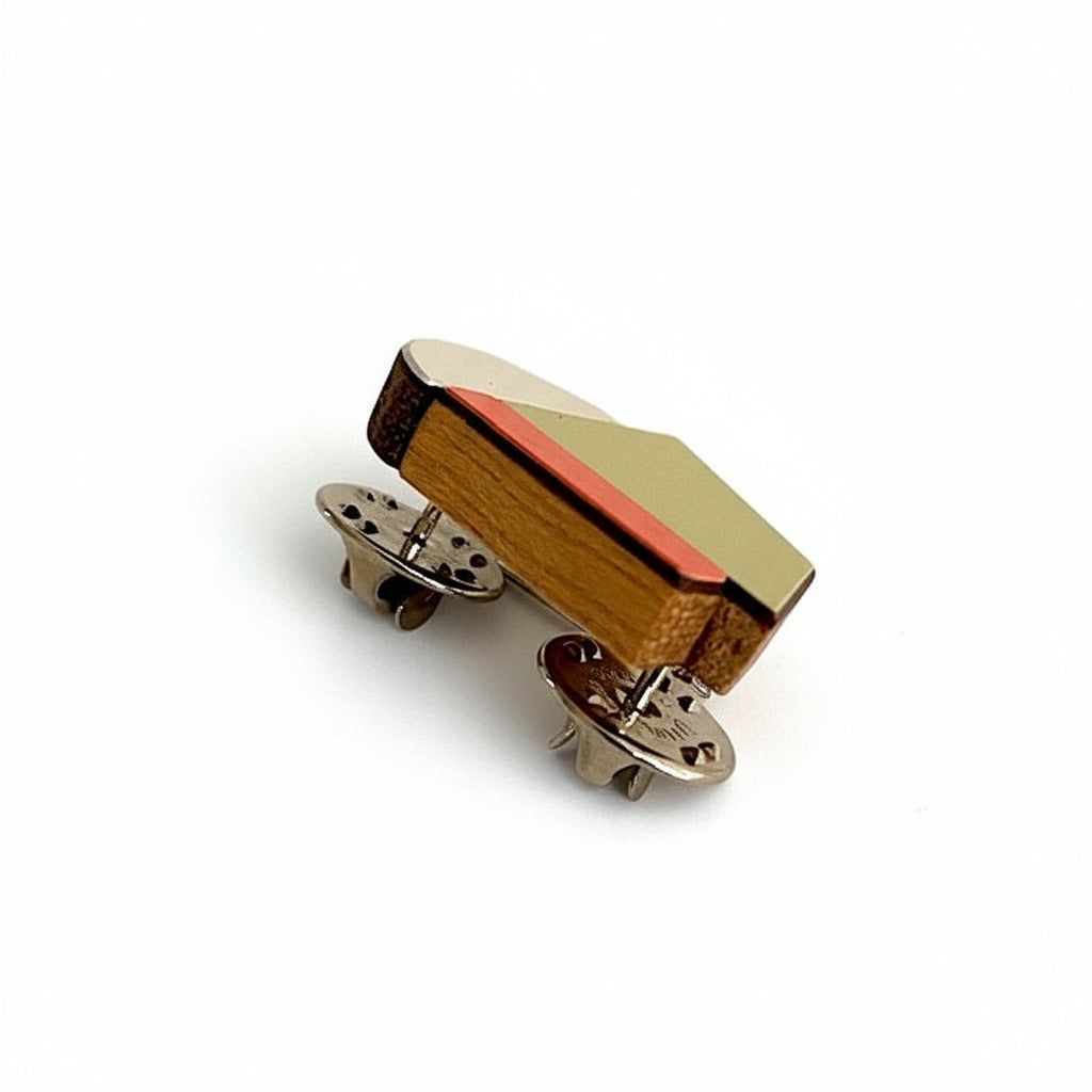 Mini broche géometrique en bois et formica orange, kaki et argenté. Ludiqu elle est faite main par l’artiste belge Karen Vanmol. Légère, elle se fixe par deux pin's d'acier.