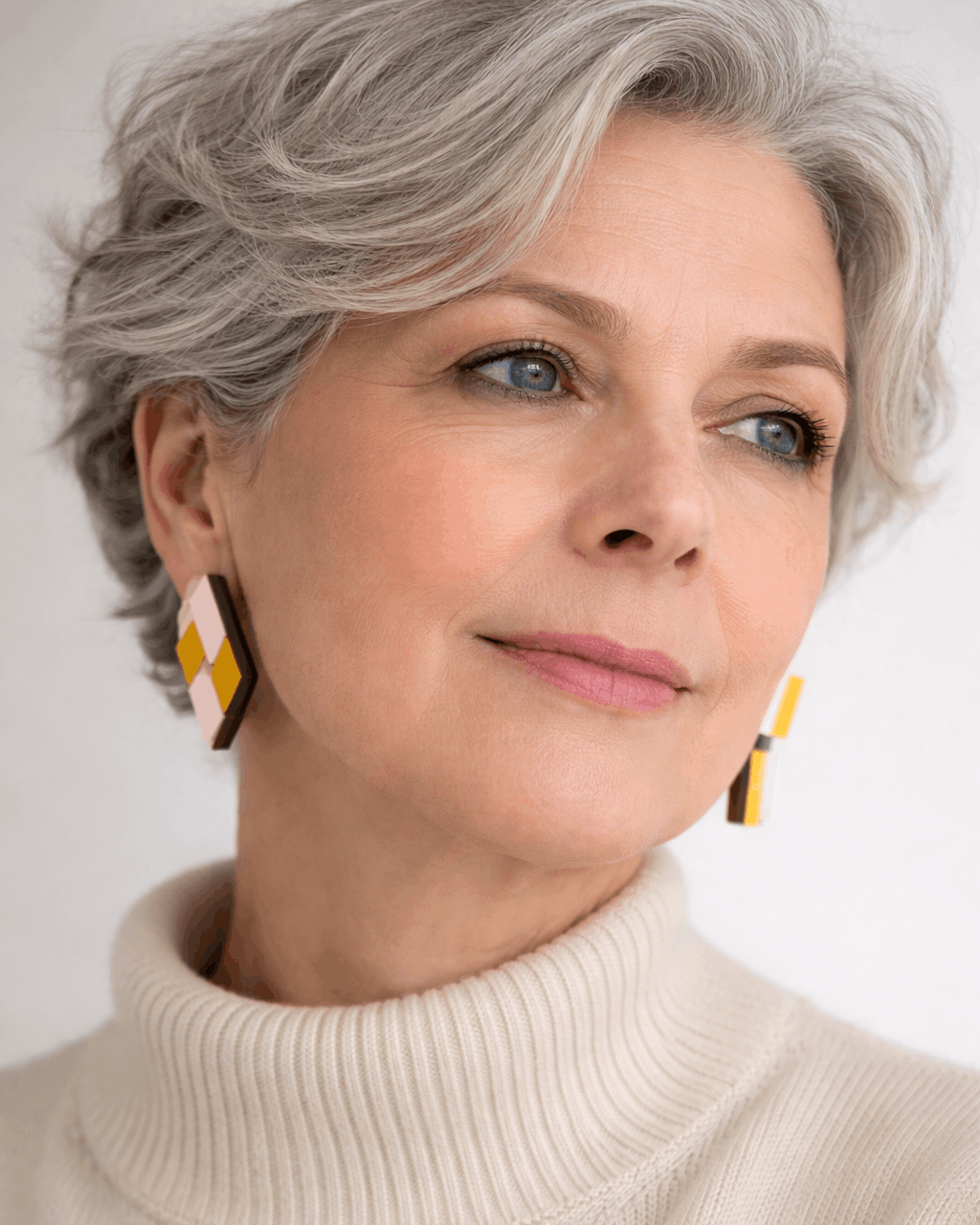 Des boucles contemporaines et asymétriques en bois et formica jaune et rose. Le modèle présente une boucle en rectangle articulé et l'autre un losange fixe. Bijoux portés.