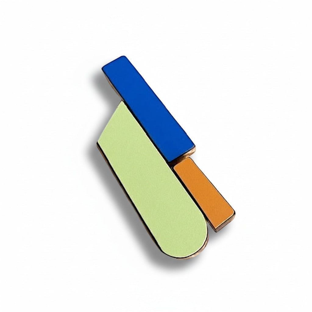 Broche contemporaine allongée en bois et formica bleu, vert et ocre orangé. Pièce unique réalisée à la main par l’artiste belge Karen.