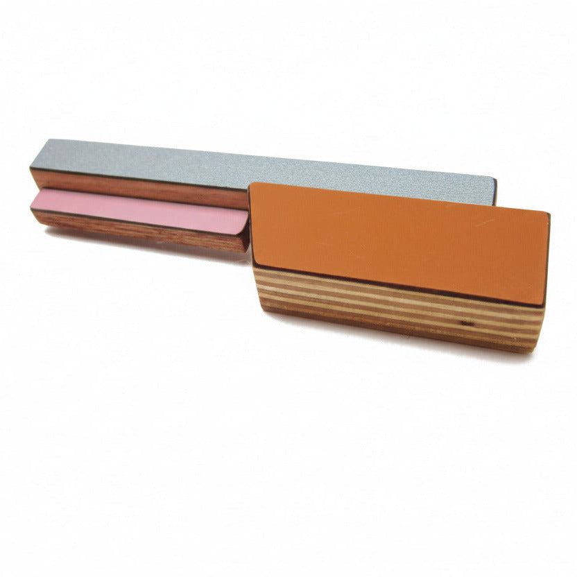 Broche contemporaine en bois et formica rose, gris et brun. Pièce unique réalisée à la main par l’artiste belge Karen, au design graphique et coloré. 