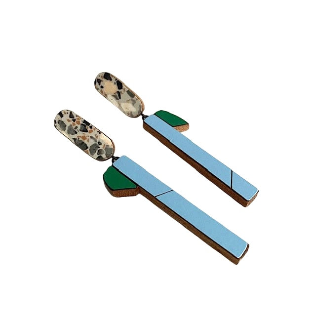 Suspendues à un support ovale en stratifié à la finition marbrée, ces longues boucles graphiques associent le bois au formica vert et bleu clair. Vue de profil.