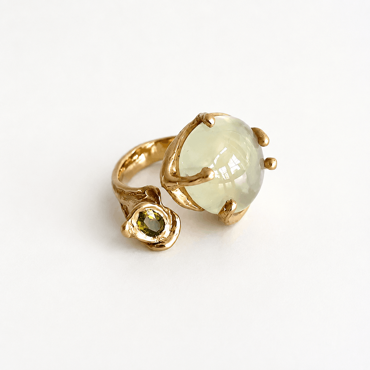 bague sculpture ouverte en bronze au forme organite avec d'un côte une grande prehnite ronde et de l'autre coté un péridot plus petit ovale et facetté.
