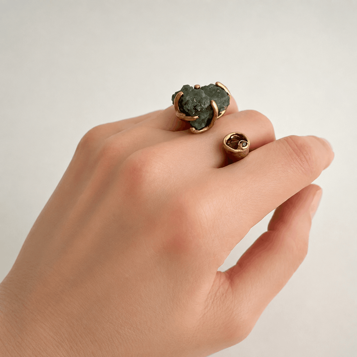 Bague ouverte en bronze sertie d'une tourmaline sculpturale verte brute et de l'autre côté une petite tourmaline taillée rose.